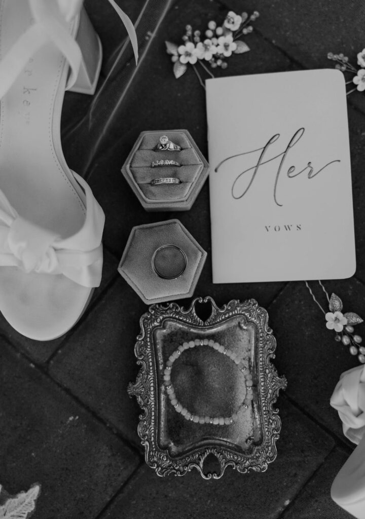 Wedding veil with white heels, her vow book, wedding rings and jewelry flat lay wedding detail photo